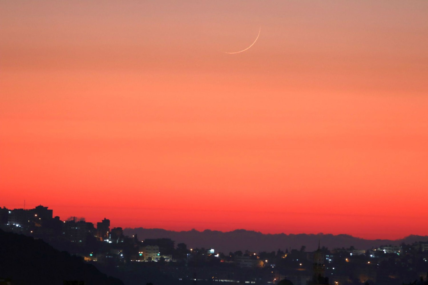 The new moon setting in the reddisn dusk sky