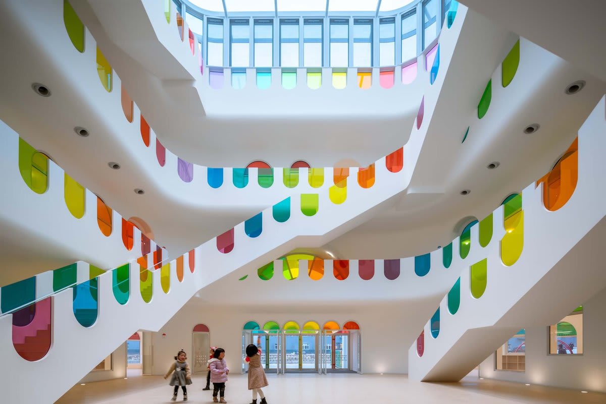 Hundreds of rainbow glass panels emit a rotating kaleidoscope in a playful kindergarten
