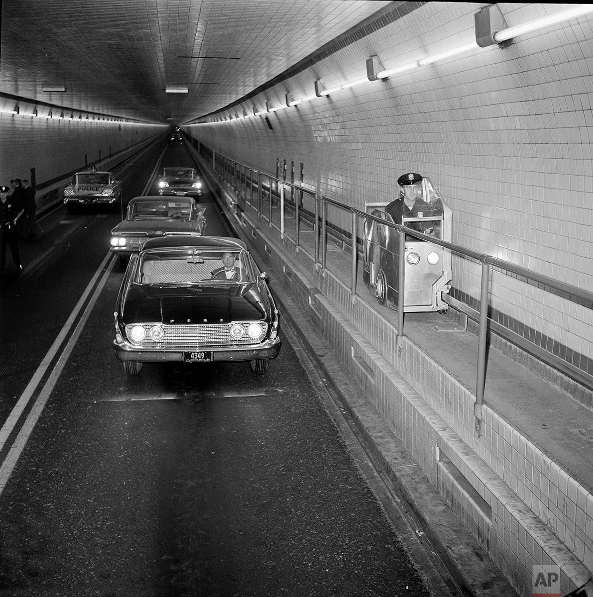 OTD in 1937, the first center tube of the Lincoln Tunnel connecting New York City and New Jersey beneath the Hudson River was opened to traffic. Photo shows a Port Authority officer demonstrate a self-propelled catwalk car near the Manhattan end of the Lincoln Tunnel in 1960.