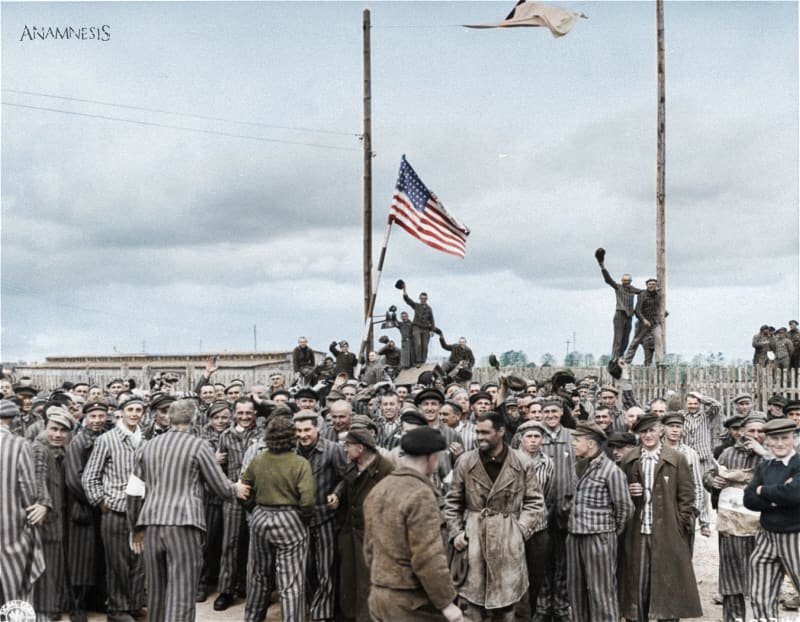 Inmates waving a home-made American flag greet U.S. Seventh Army troops upon their arrival at the Allach concentration camp. April 30, 1945. [Colorization]