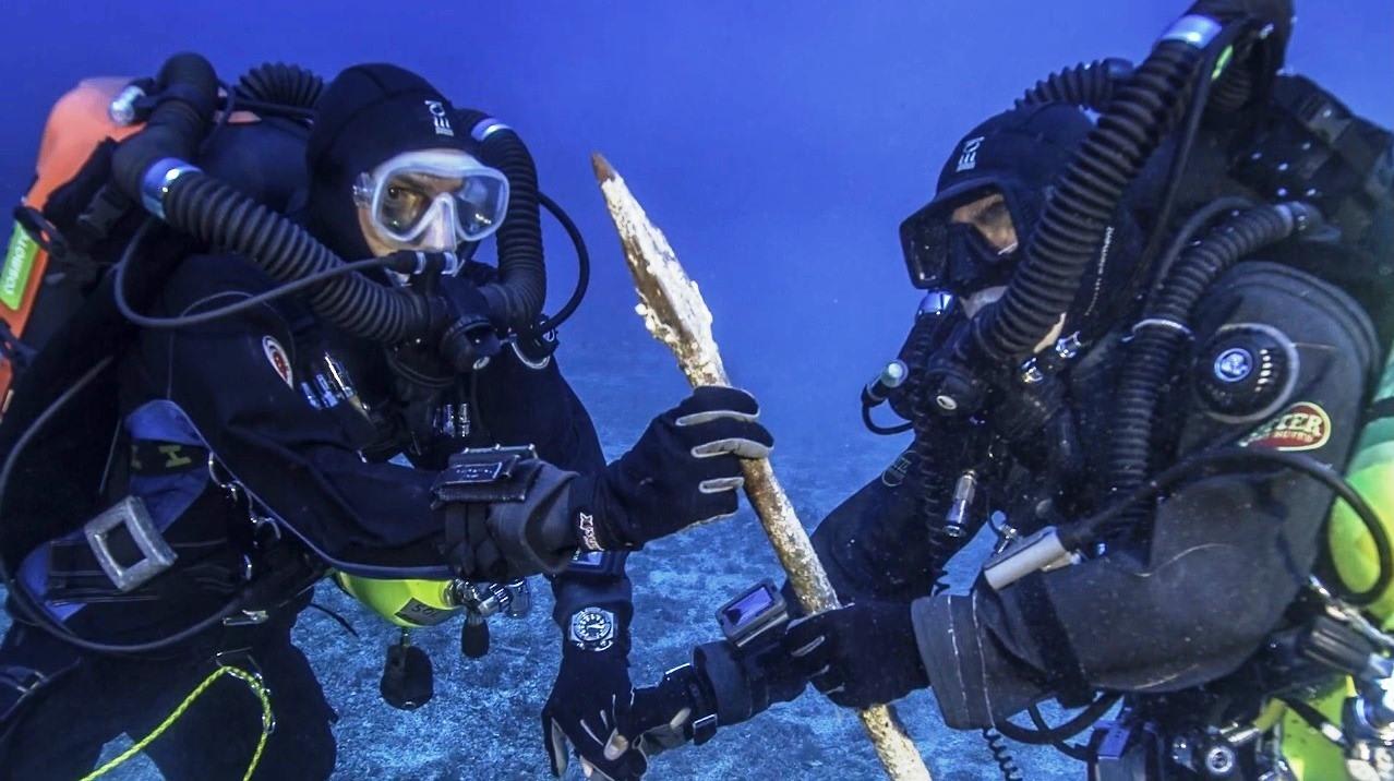 Divers examine a bronze spear that was recovered from the site of the Antikythera Shipwreck (Video in comment)