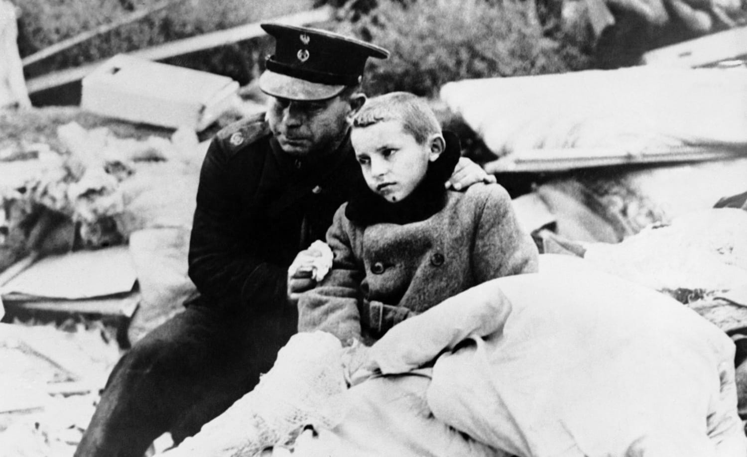 A uniformed Polish official comforts a boy whose mother was killed in an air raid on Warsaw, September 1939. The boy himself was in the wreckage for 12 hours before rescue crews liberated him.