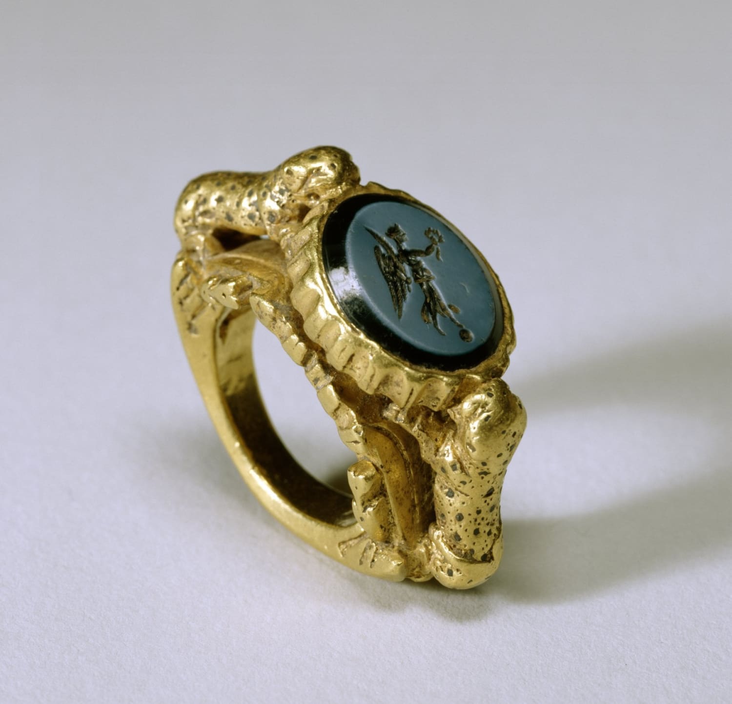 Ancient Byzantine gold ring featuring a blue nicolo intaglio carving of Nike supported by two gold leopards, 4th century CE.