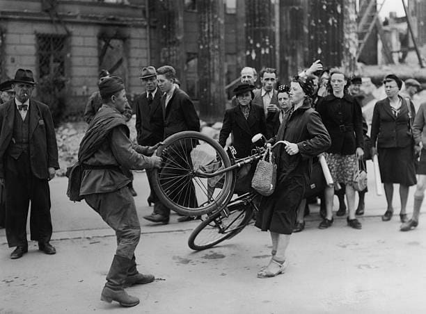 A Russian soldier involved in a misunderstanding with a German woman in Berlin, over a bicycle he wished to buy from her. 1945. Photo by Keystone