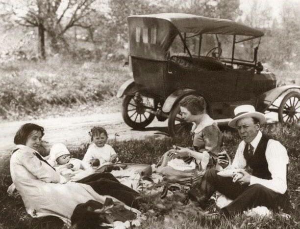 Family having a picnic by the side of the road with a Model T Ford in the background, ca 1918.