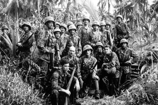 A group of United States Marine Raiders pose for photo in front of a Japanese dugout, on Bougainville, January, 1944