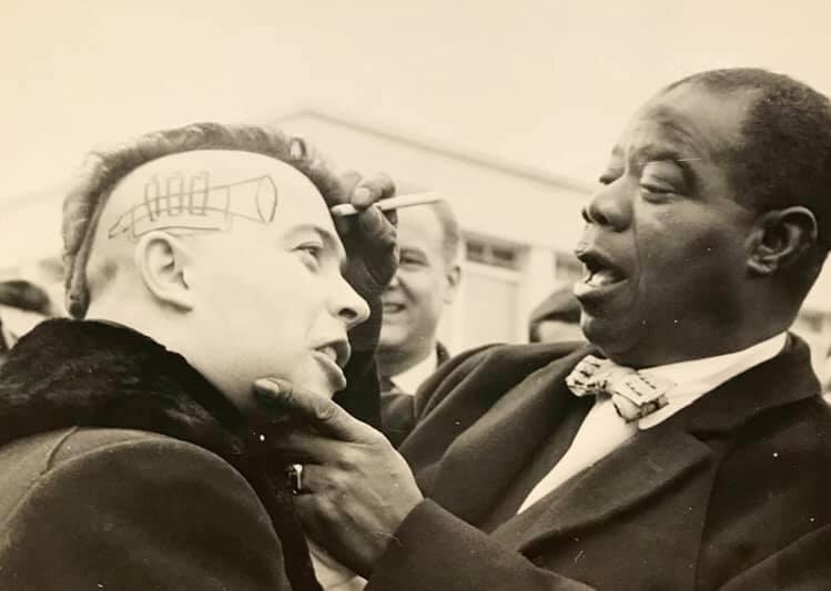 Louis Armstrong draws a trumpet and signs the side of a fans head. Nice, France,1961 .. It's crazy how the fan, because of his haircut, looks more like a punk enthusiast time traveling from the future. Anyone knows more details about this encounter ?
