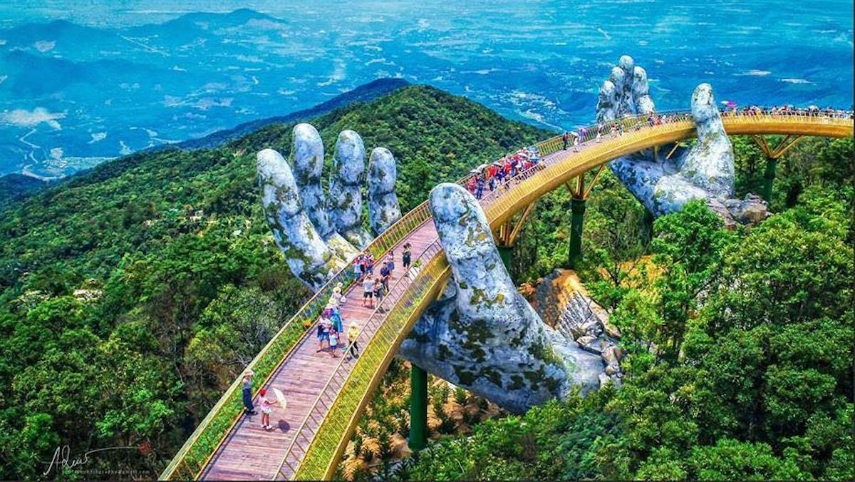 Giant weathered hands lift this new golden pedestrian bridge in Vietnam