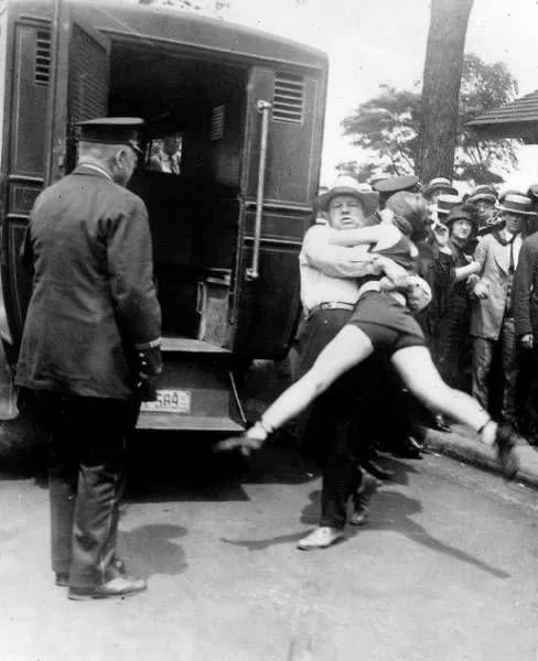 This woman is being arrested for wearing a swimsuit and having her legs uncovered. (Chicago, 1922).