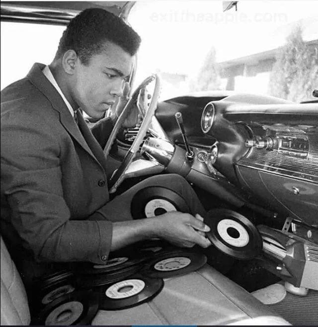 Muhammad Ali inserting a 45 into the record player of his 1969 Cadillac Eldorado.
