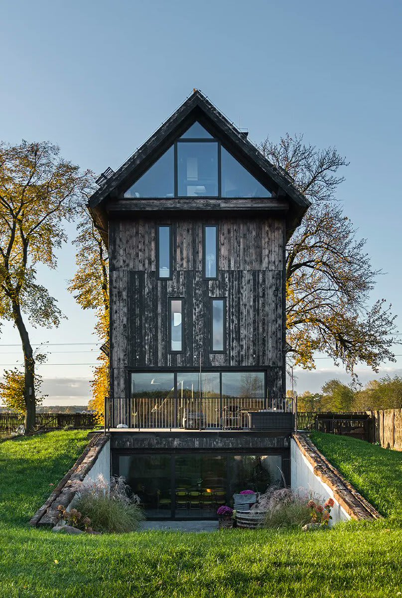this old windmill in poland has been converted into a charming and modern getaway home -- featuring glazed openings, reclaimed wood, reinforced concrete, and innovative interior accents.