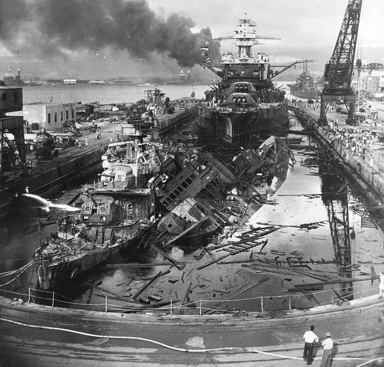 The wrecks of destroyers USS Cassin (DD-372) and USS Downes (DD-372) in the wake of the Pearl Harbor attack with battleship USS Pennsylvania (BB-38) and light cruiser USS Helena (CL-50) in the background, December 7th, 1941