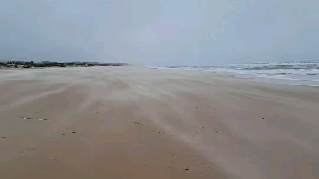 The way the wind blows the dry, white sand over the dark, wet beach looks like a constant, swiftly flowing river.