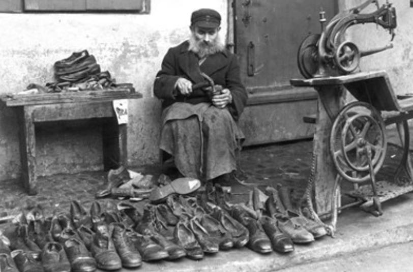 A cobbler at work on the street in the Warsaw Ghetto in Nazi-Occupied Poland, May 1941.