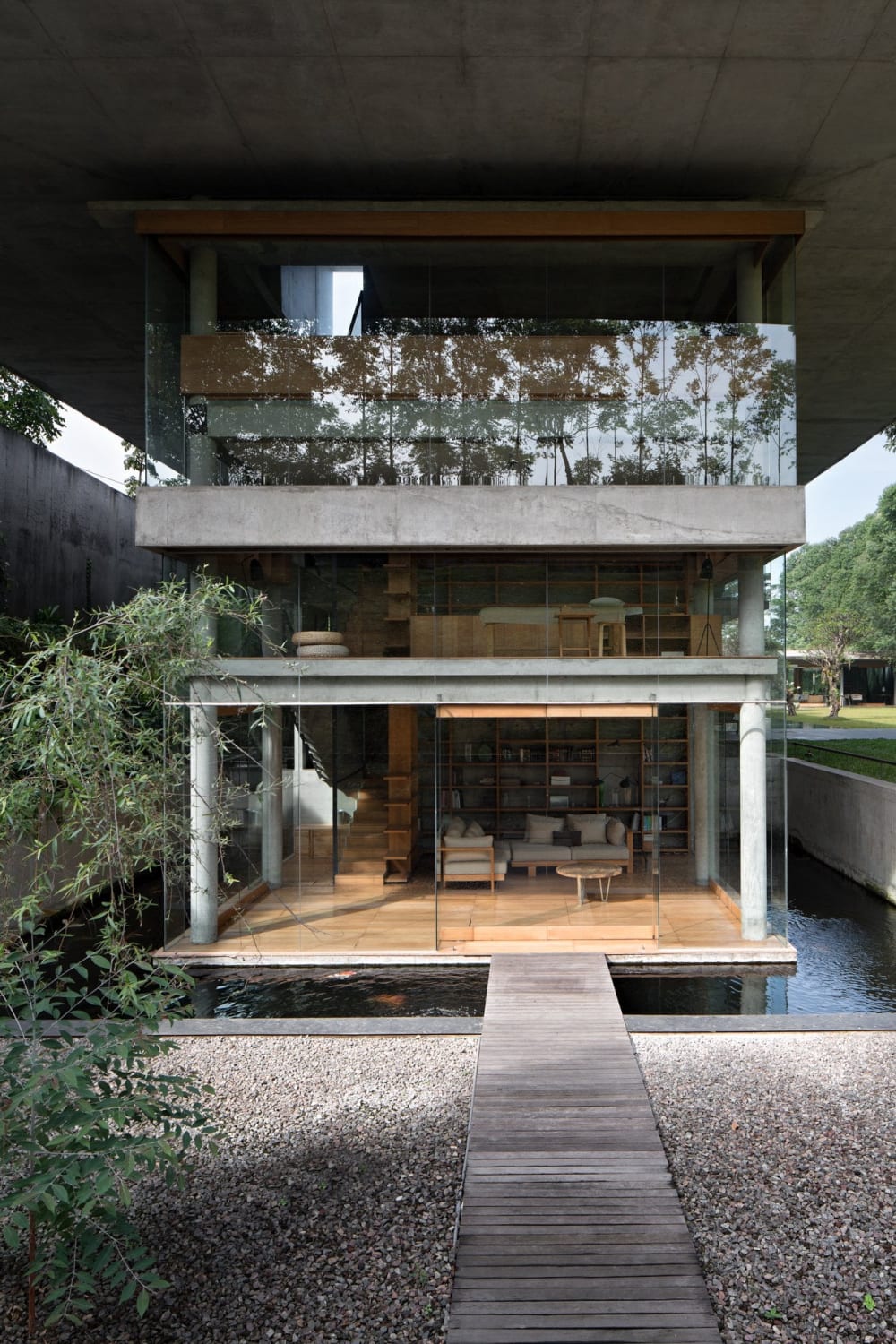 Living space surrounded by a koi pond with a bridge connected to a patio below ground level, Bandung, West Java Province, Indonesia