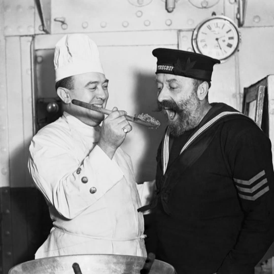 These may be history’s happiest men! A sailor gets an early taste of the Christmas pudding aboard HMS Cochrane, November 1940. © IWM A 1988