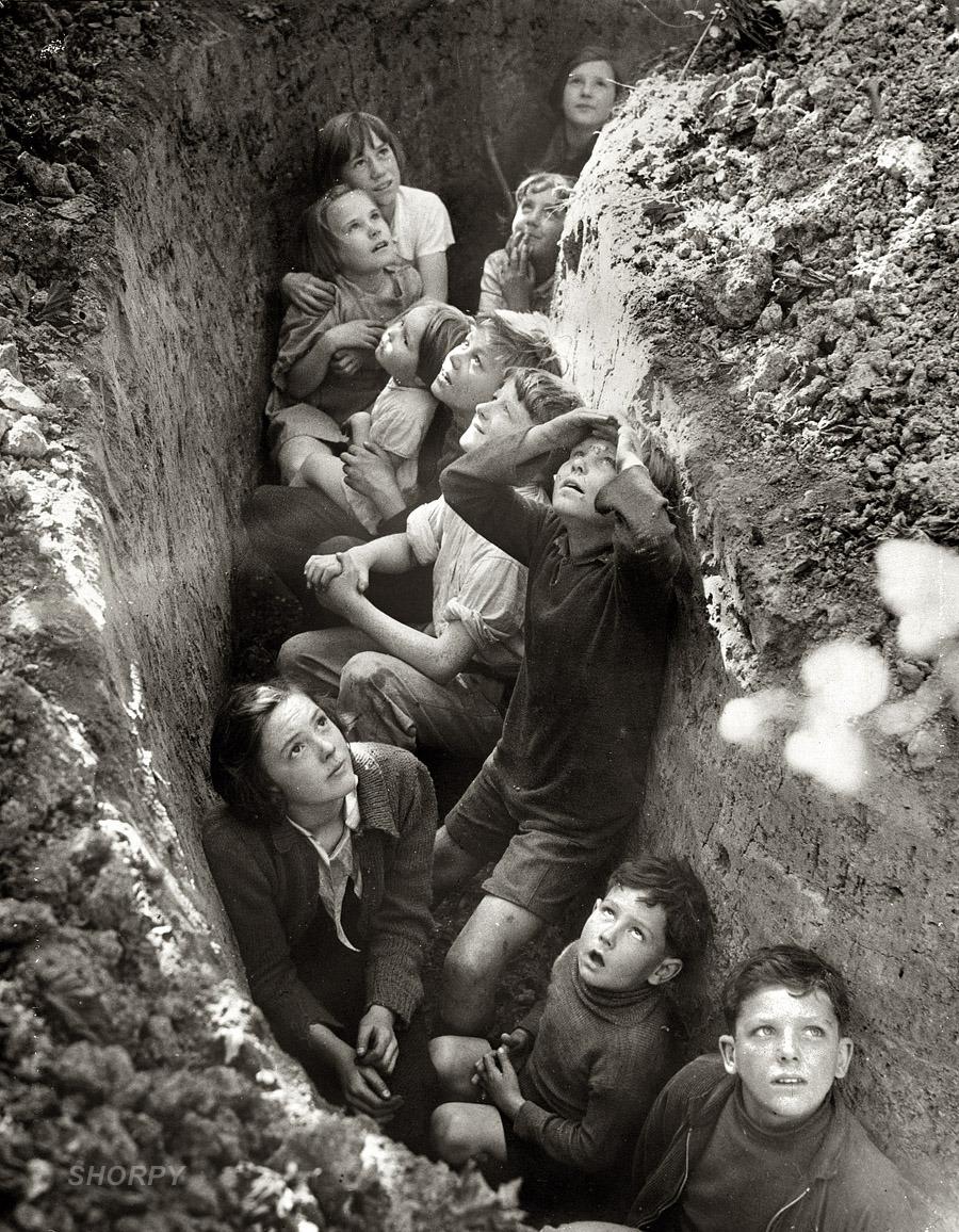 British children taking shelter in a slit trench during a German bombing raid, 1940