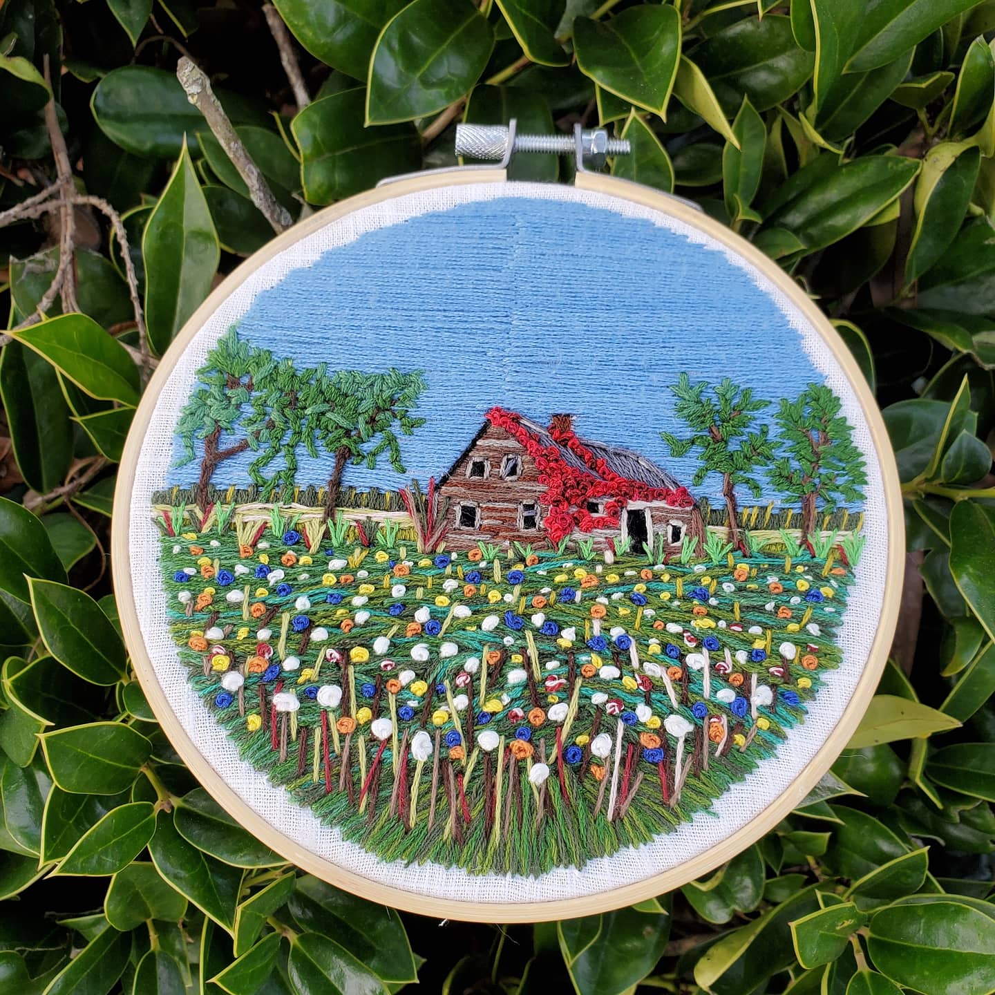 Freehand embroidery of an abandoned farm house in a field or wildflowers