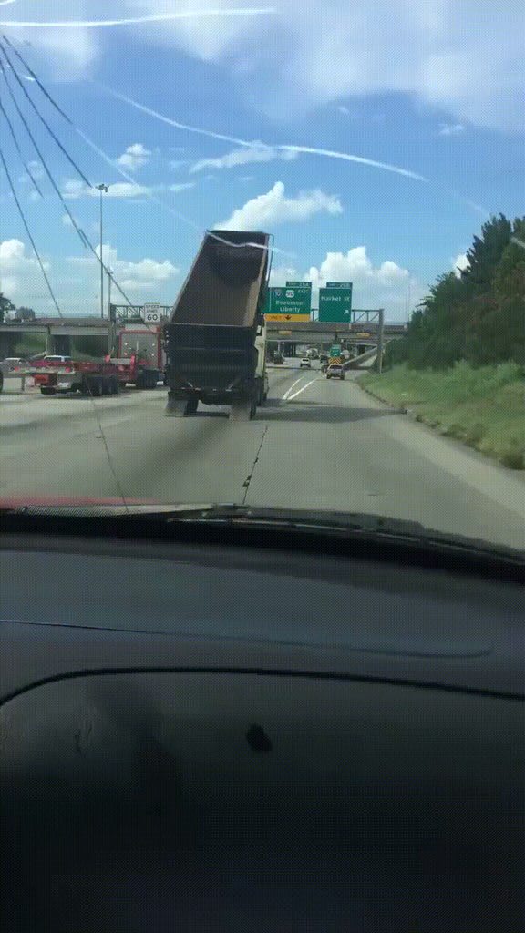 Driver narrowly avoids collapsing highway sign after a dump truck with a raised bed takes it out at high speed