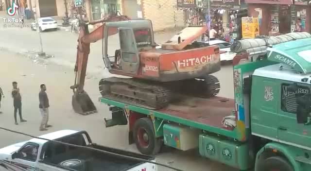 Egyptian driver loading off an excavator from a trailer truck