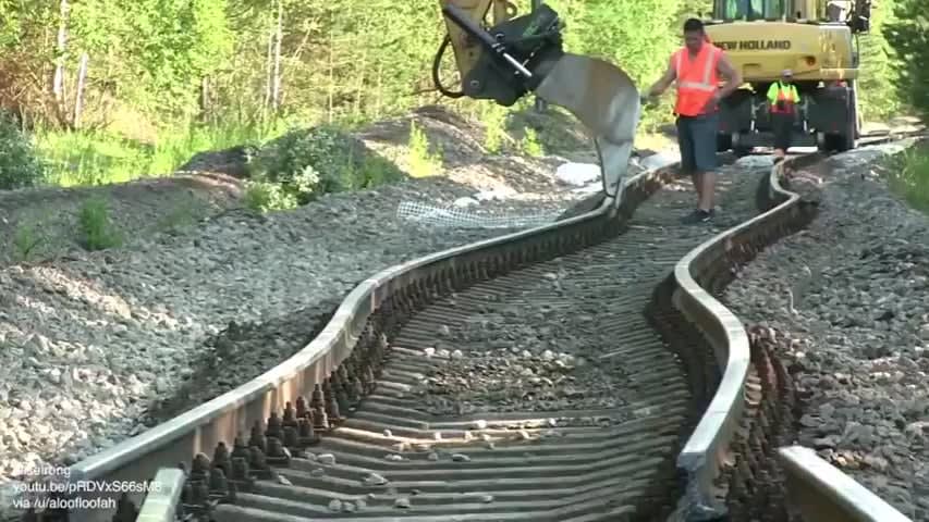 Straightening railroad tracks with a backhoe