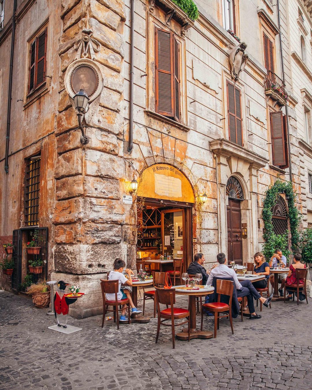 Diners outside a corner restaurant at a cobblestone street in Rome, Italy.