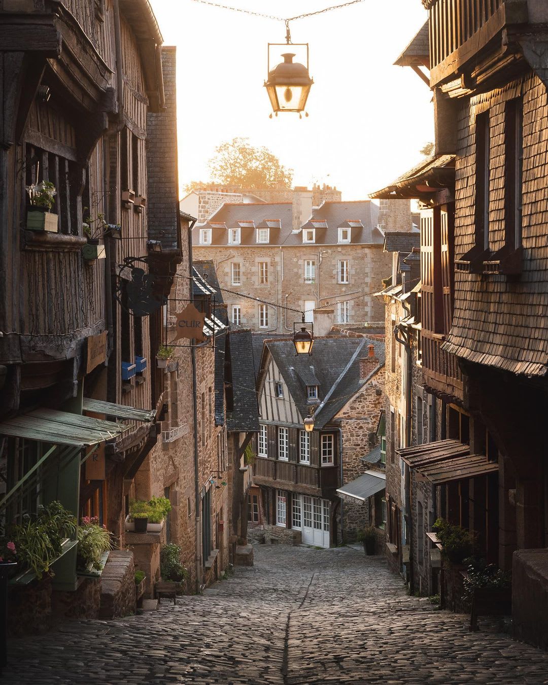Morning sunlight over a cobblestone street in the medieval walled town of Dinan, Brittany, France.