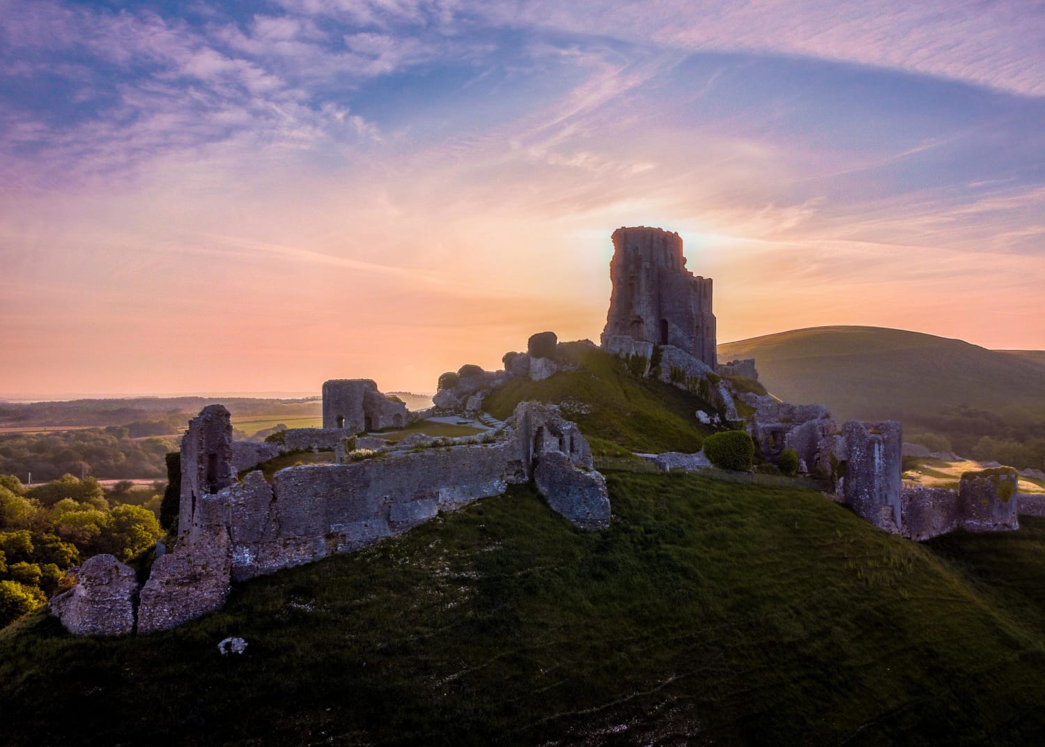 A drone shot of Corfe Castle soon after sunrise. The castle was built in the 2nd half of the 11th Century and is located in Dorset near the South Coast of England