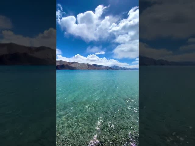Clear Blue Water of Famous Lake Washes Shore Against Beautiful Mountains - 1206356