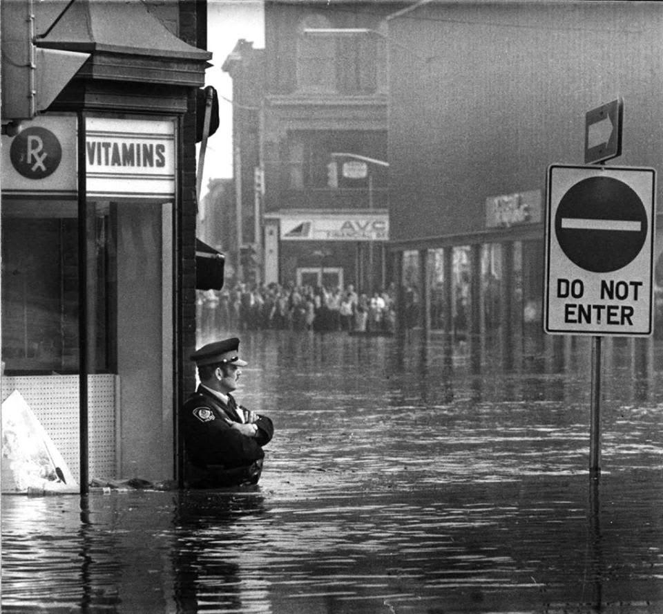 Canadian police officer guarding the pharmacy in waist-high flood waters in Galt, Ontario, May 1974.