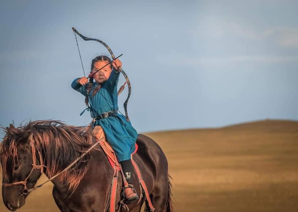 Five year old Mongolian archer girl practicing on horseback
