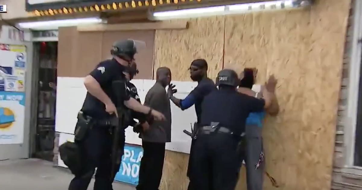 Police handcuff people trying to protect store from apparent looters, while suspects run away