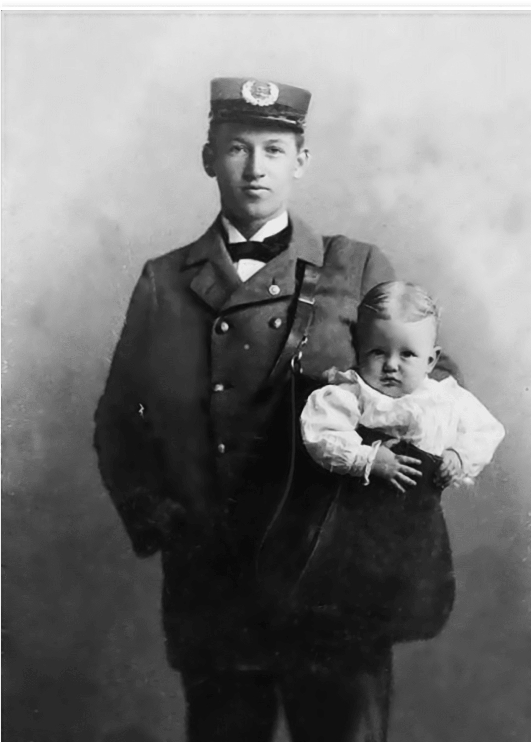 USPS Mailman posing with a baby in his bag. 1913