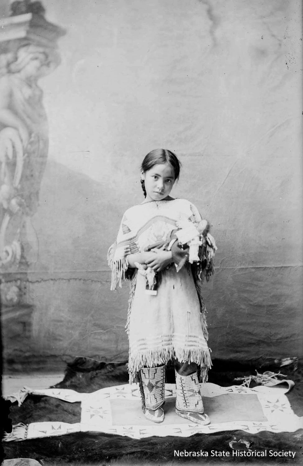Katie Roubideaux of the Rosebud Sioux tribe with her doll. Katie was the daughter of Louis Roubideaux, a French/Lakota interpreter for the Rosebud Sioux Reservation, and his third wife, Adelia Blunt Arrow - 1890