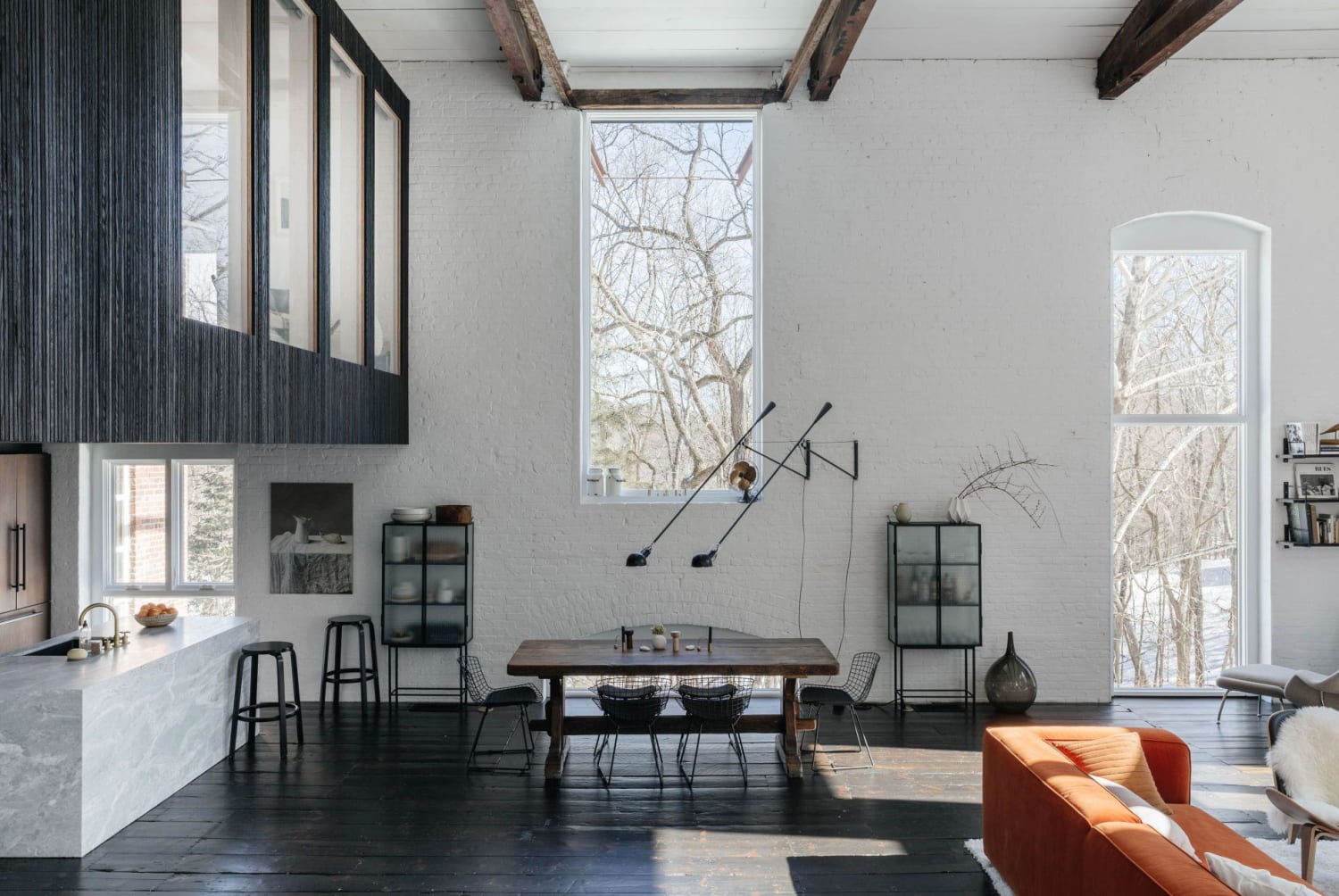 Double-height living area with a loft bedroom cantilevered above the kitchen in a former historic foundry turned home, Somers, New York by Ravi Raj Architect