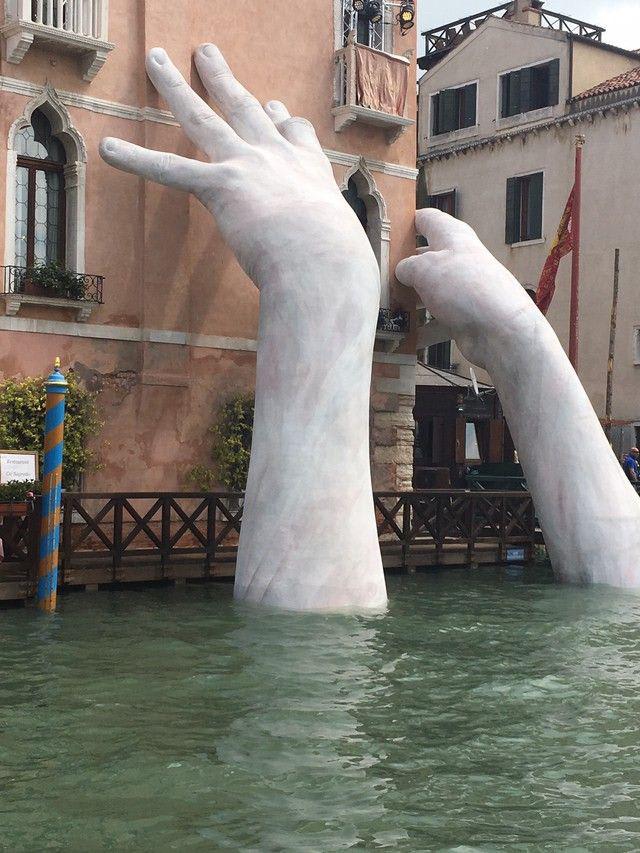 Giant Hands sculpture emerging from Venice’s Grand Canal, calling attention to climate change.