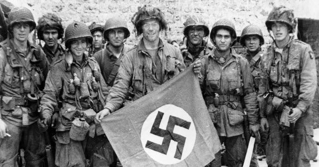 101st Airborne troops posing with a captured Nazi flag two days after landing at Normandy, June 8, 1944.