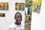 15-year-old Saviour from Kibera poses next to paintings during his ongoing solo exhibition at Kuona Trust - an artists' collective space in Nairobi. Saviour is the youngest artist among the collective. Photo by © Bryan Jaybee
