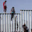 Migrants climb over fence as caravan arrives in Tijuana