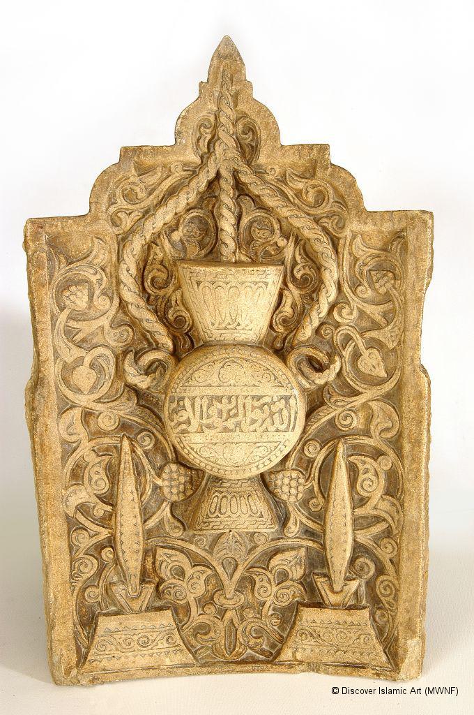 A Mamluk marble plaque with a mosque lamp carved in the center and suspended from the crown by thick ropes. 14th century CE, found at the Madrasa Bedeiriyya, now on display at the Museum of Islamic Art in Cairo
