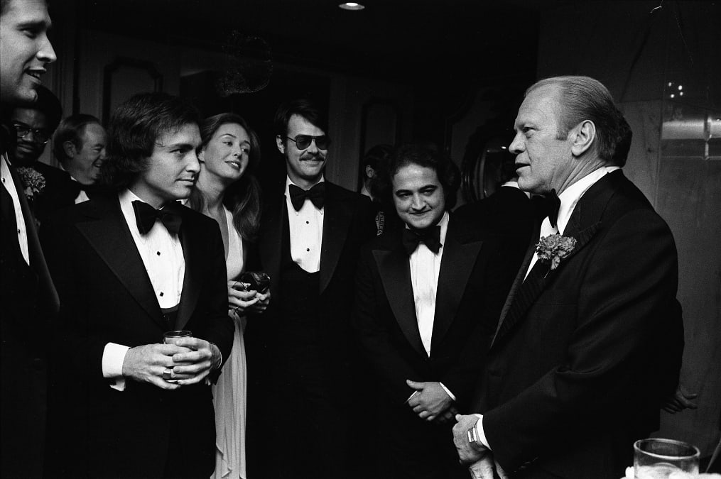 President Gerald R. Ford Talking with Chevy Chase, Saturday Night Live Producer Lorne Michaels, John Belushi, Dan Aykroyd, and Others at the 32nd Annual Radio and Television Correspondents Association Dinner, OTD in 1976