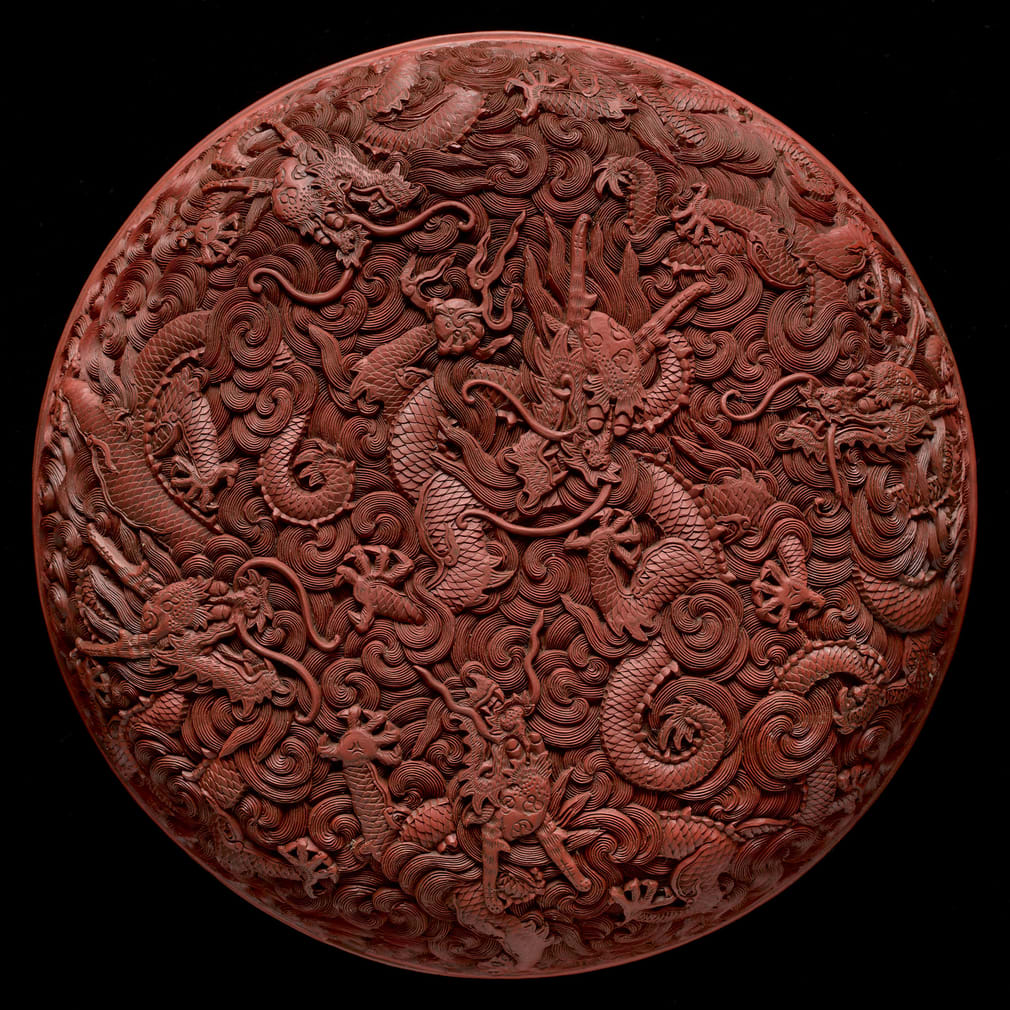 A cover of a circular imperial boxe depicting five five-clawed dragons emerging from waves. Red lacquer on wood, from the reign of Qianlong, 1736-95, part of the Royal Collection Trust