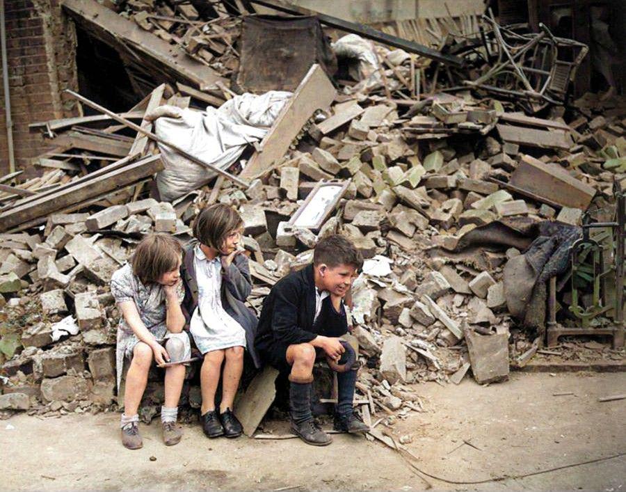 Children of an eastern suburb of London, who have been made homeless by German bombings, sit outside the wreckage of what was their home, September 1940 [Colorized]