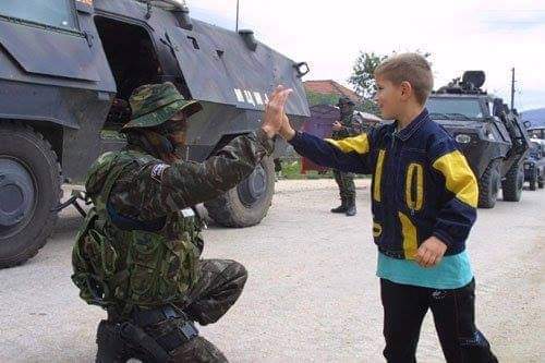 A Macedonian police Special Forces operator from the "Lions" unit high-fives a local boy in a village around Tetovo. The unit was deployed to quell the KLA terrorists during the Albanian insurgency in 2001.