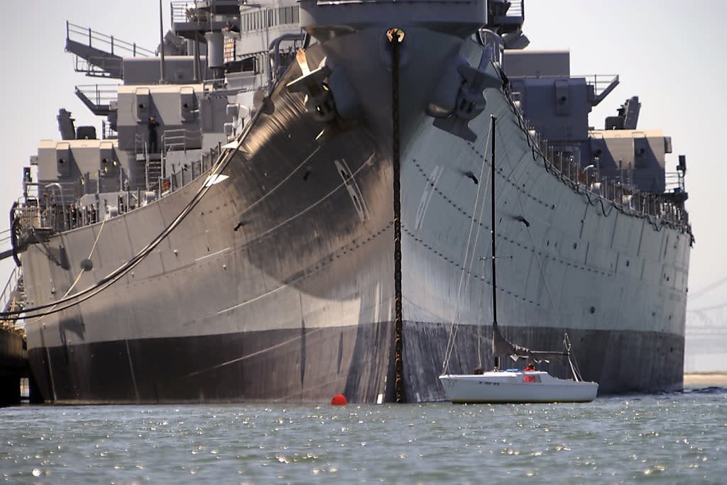 Sailboat in comparison to a moored USS Iowa.
