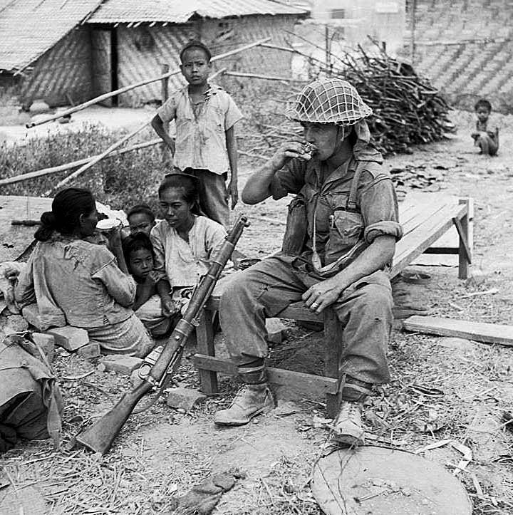 Burma Campaign. Battle of Meiktila. January – March 1945. A British squaddie enjoys a cup of tea with a Burmese family.