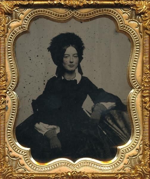 Ambrotype of a young woman with a slight smile, wearing a fur hat and leather gloves, holding a riding crop, c. 1850s ✨
