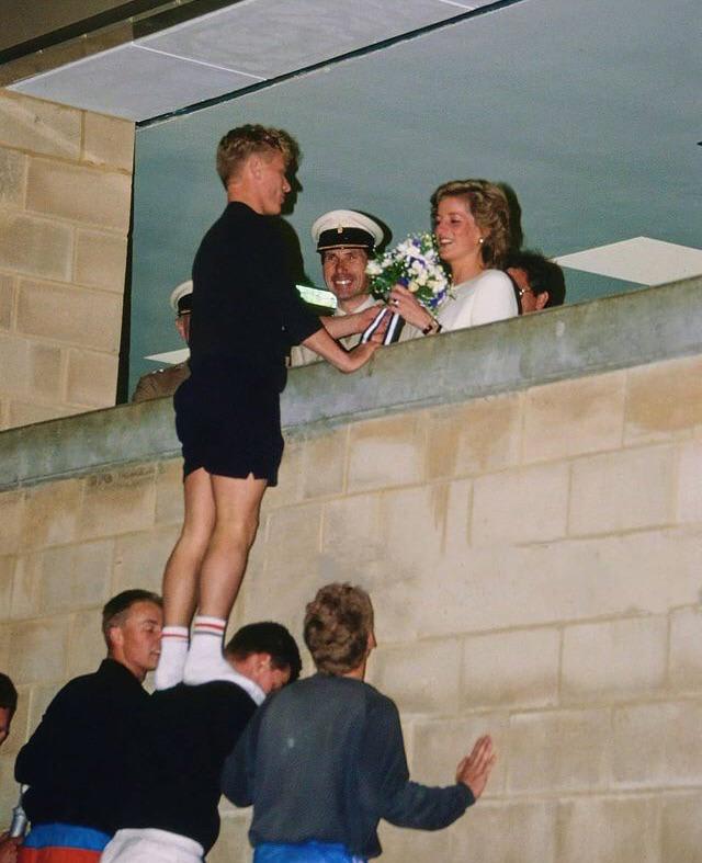 A teenage boy giving flowers to Princess Diana with the help of his friends