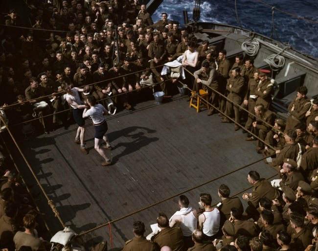 British soldiers watching a boxing match on a troop ship from England to North Africa, 1943. (Original color photo by Robert Capa)