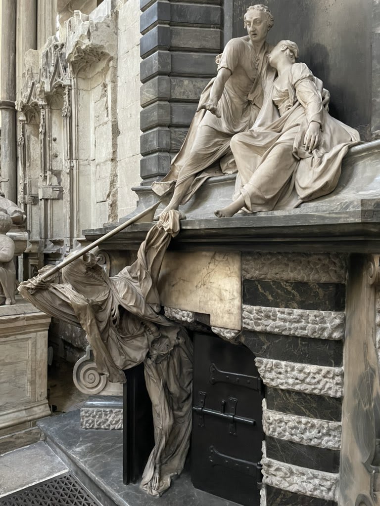 Joseph Nightingale tries in vain to protect his wife as death emerges from the locked vault. Death is partially shrouded and missing a jaw. The dramatic Nightingale monument by Roubiliac at Westminster Abbey.